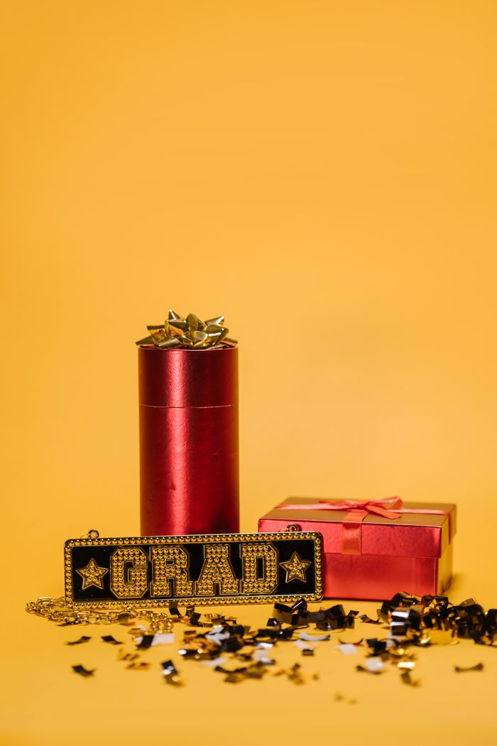 Close-up of graduation gifts with confetti on a yellow background.
